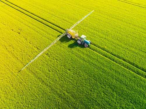 Trekker met landbouw sproeier voor gewassen in een veld van boven