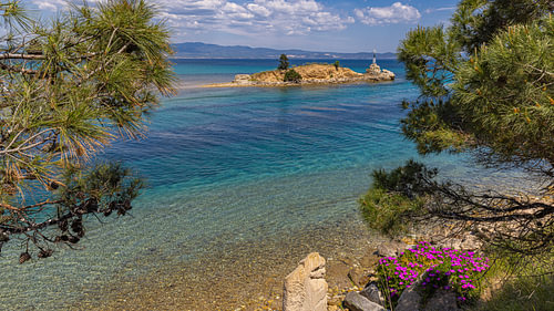 Vue à travers les pins sur une île dotée d'un phare, dans le canal de Nea Potidea