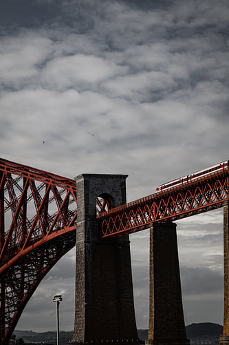 Trein over een oude rode brug in South-Queensferry, Schotland.