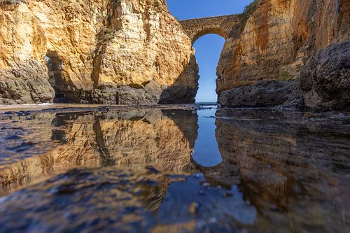 Zonsondergang bij Praia da Caldeira. Kliffen een brug over de zee van een baai bij Lagos, Portugal