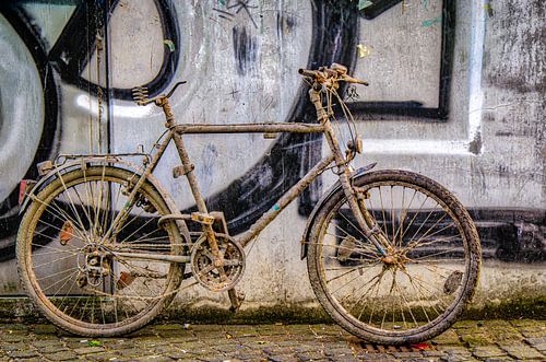 Old dirty bike on wall with graffiti