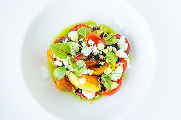 Kleurrijke salade gepresenteerd op wit bord van John Stijnman