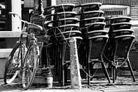 Bicycle against pole with stacked chairs