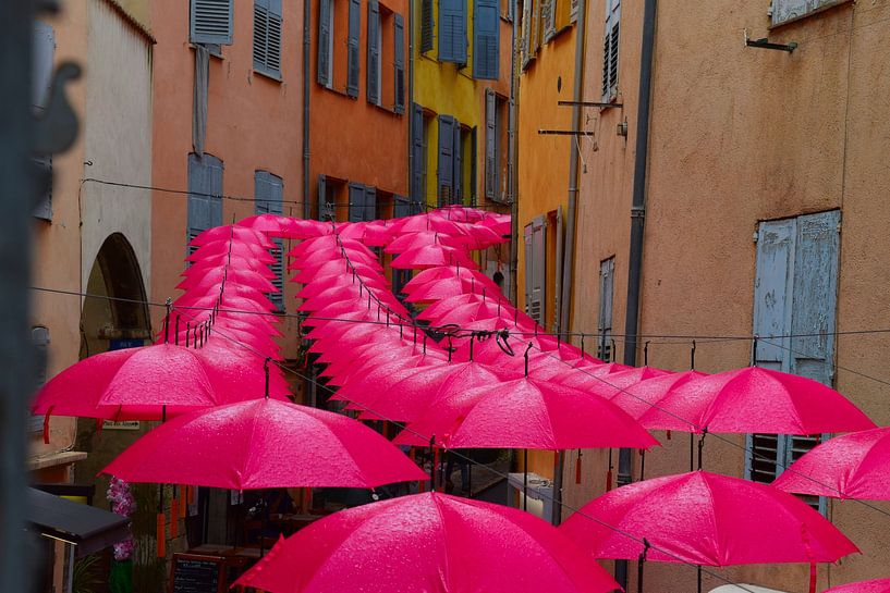 Brightly coloured, cheerful pink umbrella&#039;s lined up in downtown Grasse, in the rain by Studio LE-gals
