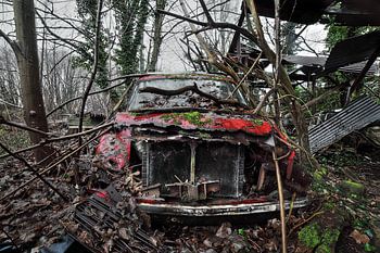 Urbex red heavily dilapidated car in the forest