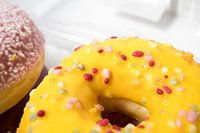 Closeup van geglazuurde donuts met een witte achtergrond.
