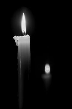 Eine brennende Kerze mit einem Spiegelbild im Hintergrund von Quirina Kamoen
