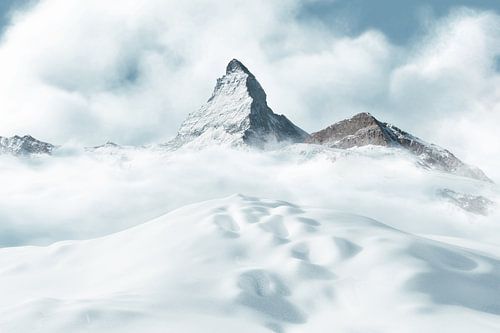 Besneeuwde heuvel met sneeuwsporen voor de majestueuze berg Matterhorn