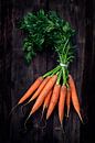Bunch of carrots with fresh green leaves on a dark rustic wooden board, top view from above, concept by Maren Winter thumbnail