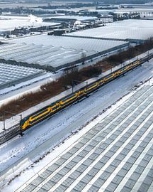 An NS train passing snow-covered greenhouses in the Netherlands by Ewold Kooistra