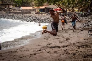 Un garçon africain joue au football sur la plage