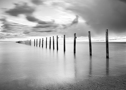 Strand Noordzee palen in het water in zwart-wit