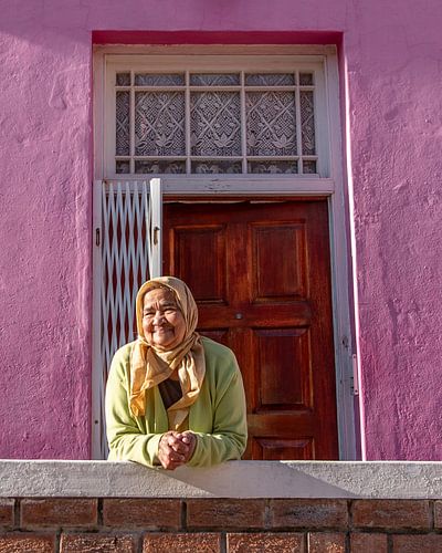 Vrouw in groen voor roze huis | Urbanfoto Afrika