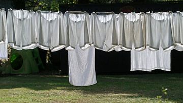 Le linge blanc pend pour sécher dans un magnifique contre-jour dans une ferme