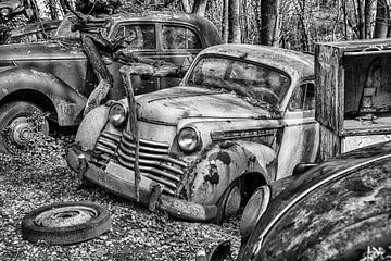 Car graveyard with old-timers and a ford olympia from the fifties in black and white van Elles Rijsdijk