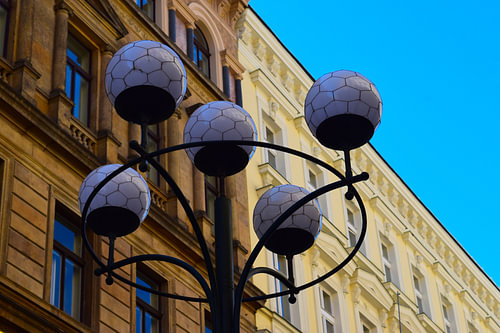 Typischer runder Laternenpfahl mit dekorativen Glühbirnen in Prag, Tschechische Republik, vor klassischer Fassade oder Fassade