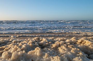 Woelige baren en schuim op Noordzeestrand