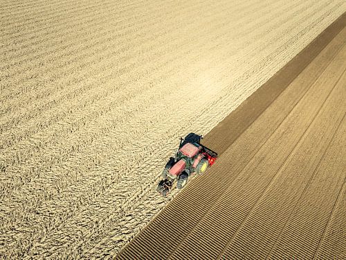 Tractor bewerkt de grond in de lente van bovenaf gezien