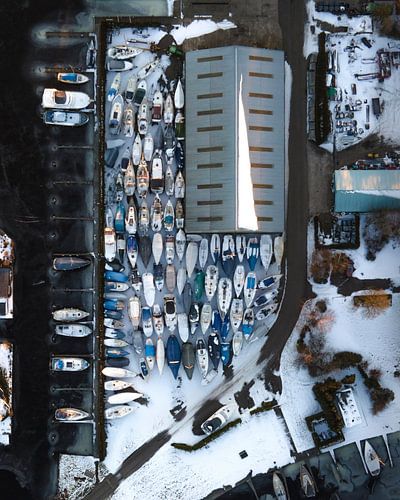 Luchtfoto van boten in winterstalling met sneeuw in Nederland