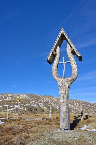 Marterl aus Holz in den Bergen vor blauem Himmel