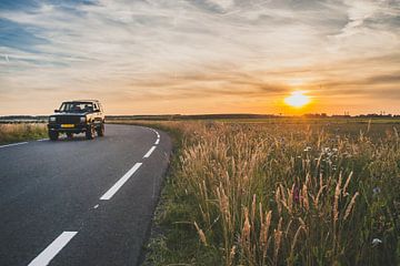 Rijdende auto in de avondzon op asfaltweg