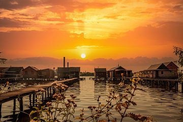 Romantische zonsondergang over een meer met houten huizen van Fotos by Jan Wehnert