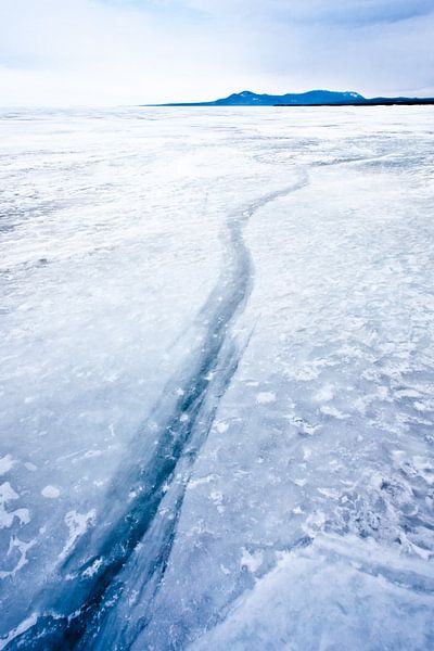 Blue crack stretching into the distance on Lake Baikal with mountains and sky by Michael Semenov