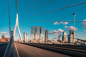 Op de erasmusbrug van Rotterdam met de Rotterdammer op de achtergrond en een blauwe lucht. van Jolanda Aalbers