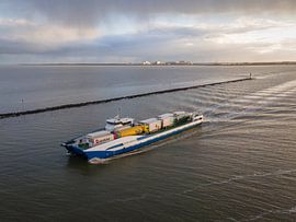 Cargo ship on the Wadden Sea in winter light by Ewold Kooistra