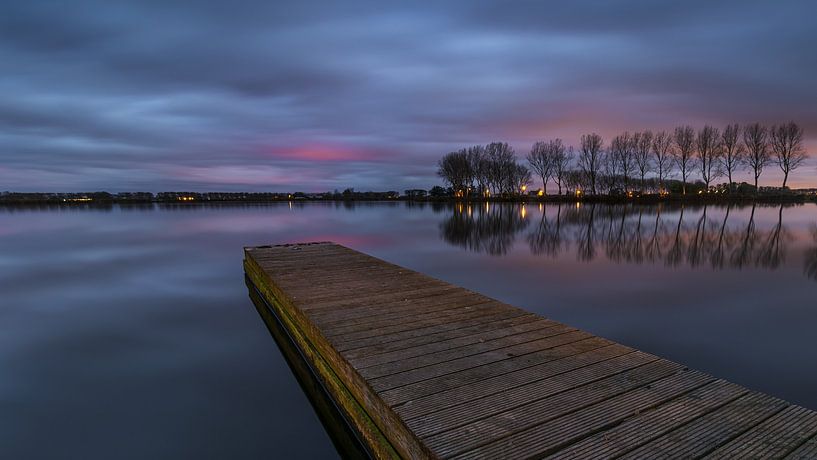 Houten steiger en bomen bij het Meer van Dirkshorn onder wolkendek tijdens de schemering van Bram Lubbers