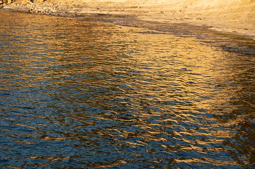 Une surface d'eau dorée dans une baie de la Méditerranée sur Adriana Mueller