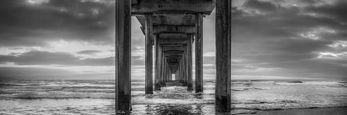 Bridge at the sea in the sunset in black and white .