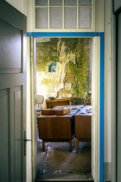 Verlassener Büroraum mit bröckelnder Wand und altem Schreibtisch von InfiniteArtLabs