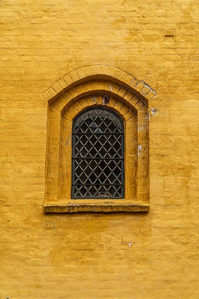Church window in ochre wall. by Axel Weidner