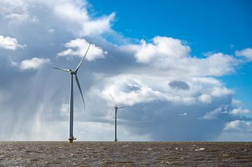 Off shore windturbines met een stormachtige blauwe lucht op de achtergrond