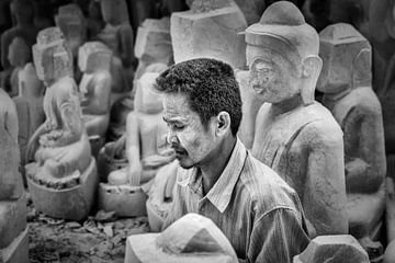 Beeldhouwer aan het werk zittend tussen Budha beelden in Mandelay aan de Marble Road