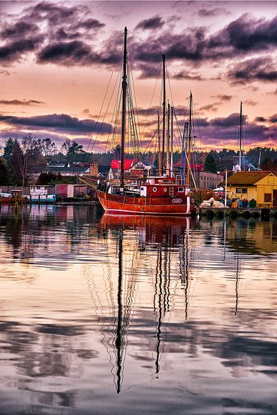 Fishing boat lies in the harbour and is reflected in the water by Stefan Dinse