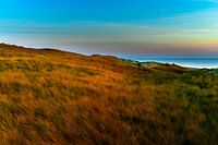 Duinen verlicht door de zon tijdens zons ondergang
