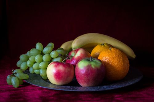 Stilleven van fruitschaal met vers fruit op warm rode achtergrond
