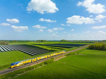 Train of the Dutch Railways driving past a field of solar panels by Sjoerd van der Wal
