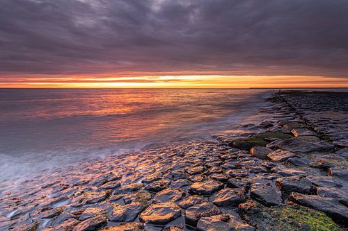 Sea pier in the North Sea under a colourful cloud cover during sunset