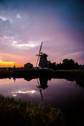Zonsondergang op een dijkje in west friesland met een molen op de achtergrond
