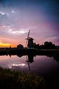 Zonsondergang op een dijkje in west friesland met een molen op de achtergrond van Lindy Schenk-Smit thumbnail