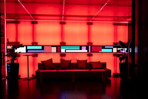 Neon-rot erleuchtete Hotel-Lobby mit schönen Lichteffekten und gemütlichem Sofa