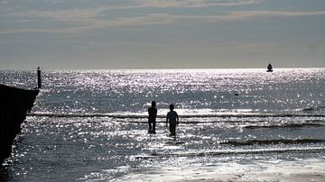 Schittering in de zee met silhouet van spelende kinderen van Wendy Duchain