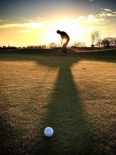 Golfer on the green at sunset