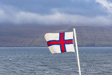 Flag in front of the rocks of the Faroe Islands with clouds