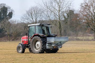 Rode tractor met automatische kalkspreider