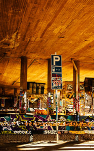 Graffiti unter der Brücke – Parkplatzschild & goldenes Licht