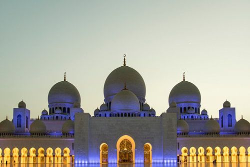 View of the blue-lit Sheikh Zayed Grand Mosque in the evening in Abu Dhabi, United Arab Emirates